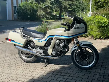 Bílá Honda CBX 1000 s kapotáží a kufry zaparkovaná na dlažbě